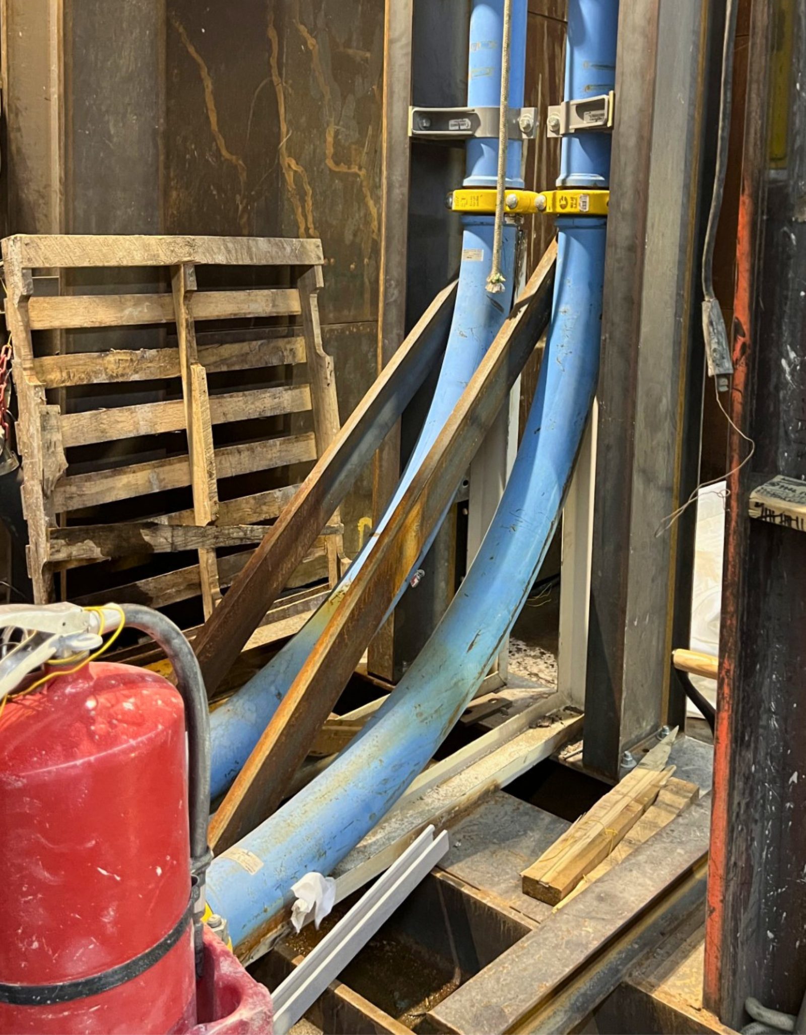 Stacked wall bracket clamps holding twin riser lines down a high-rise shaft